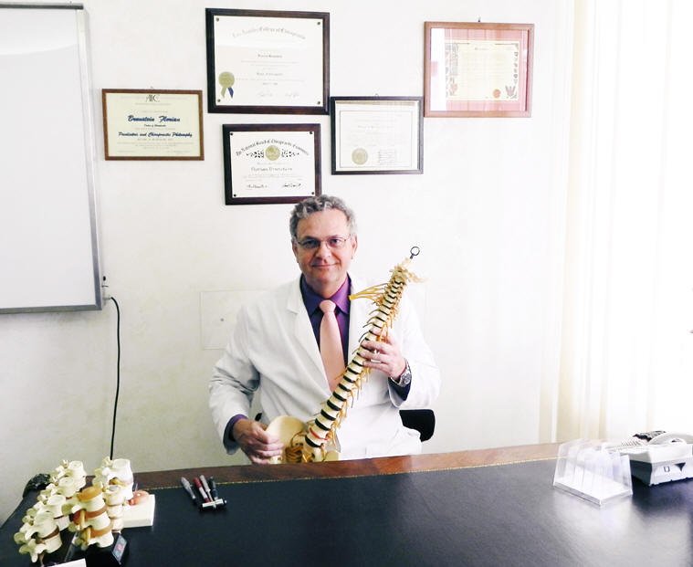 Il Dr. Florian Brunstein nel suo studio a Roma EUR, con i diplomi di Medico Chirurgo e Doctor of Chiropractic esposti alle pareti